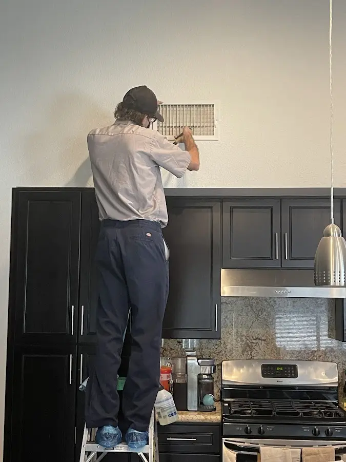 Technician inspecting an air vent during HVAC service in Annandale